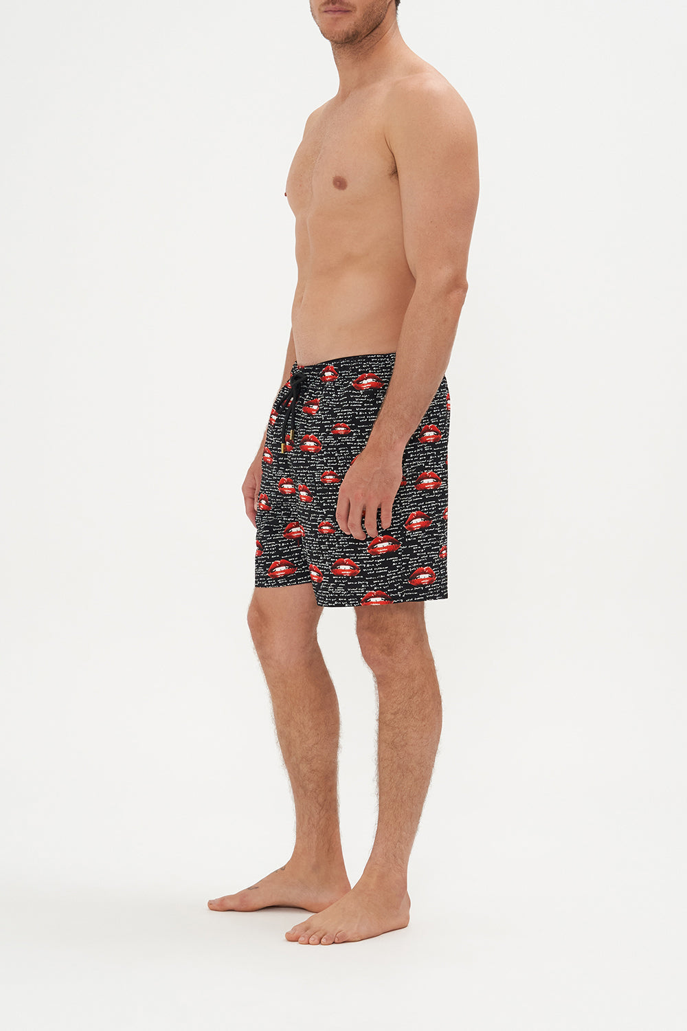 Side view of model wearing Hotel Franks by CAMILLA mens elastic waist boardshorts in black Chaos Magic Print