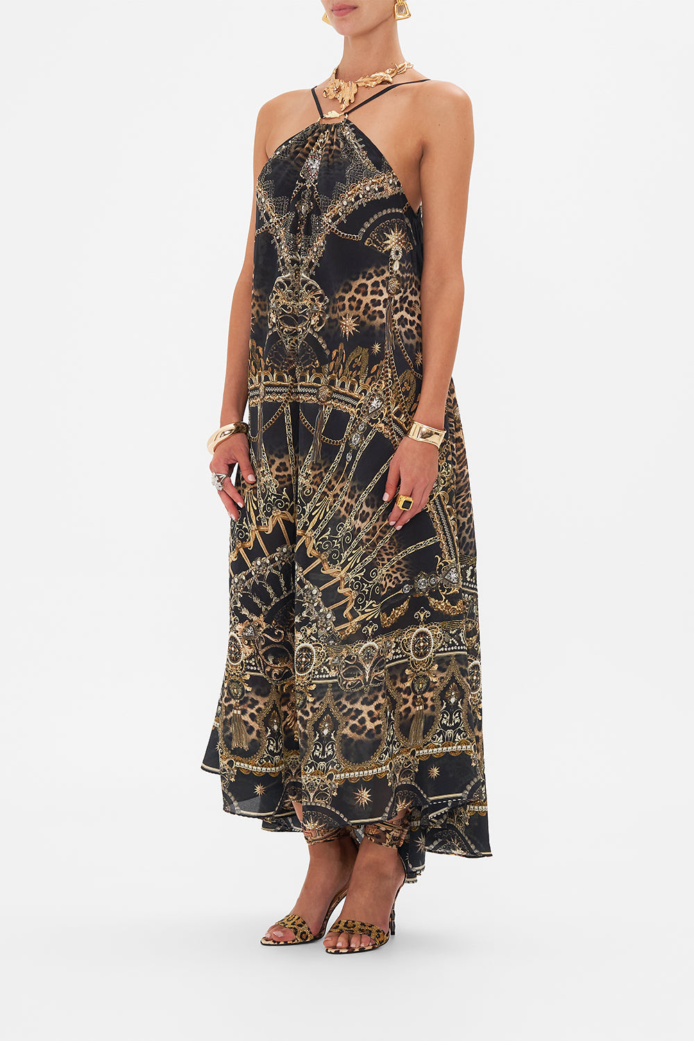 Side view of model wearing CAMILLA designer halterneck maxi dress in masked At Moonlight print