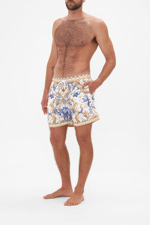 Side view of model wearing Hotel Franks by CAMILLA mens white boardshorts in Soul Searching print