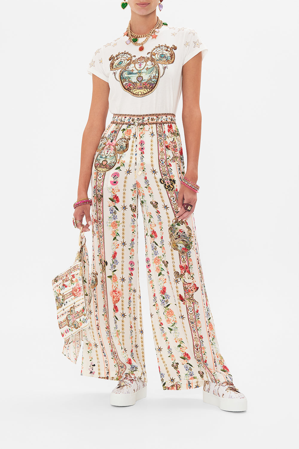 Front view of model wearing Disney x CAMILLA silk pants in Minnie Magic Forever print