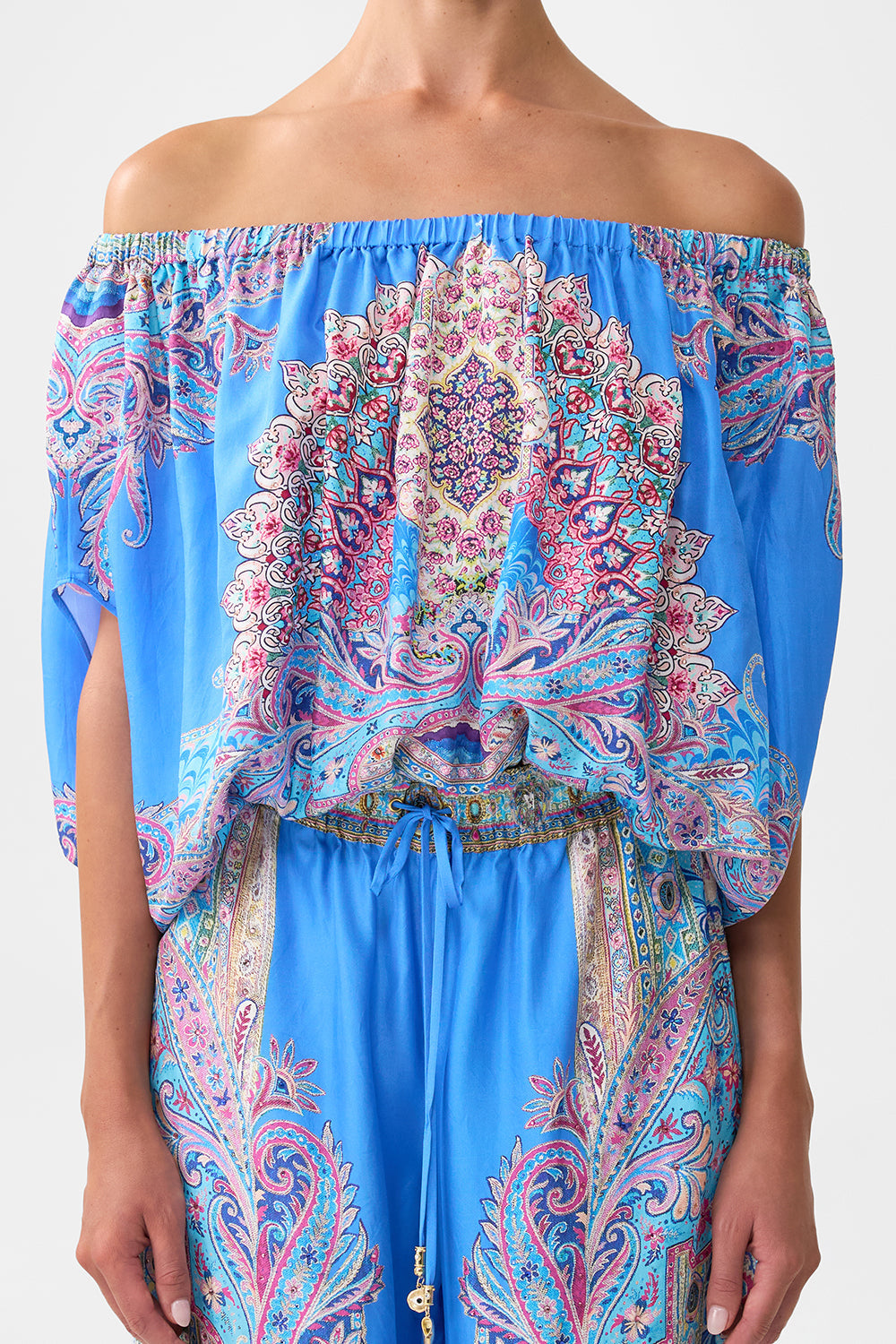 The CAMILLA OFF SHOULDER ELASTIC TOP FOOTSTEPS IN FOLKLORE in our  print.