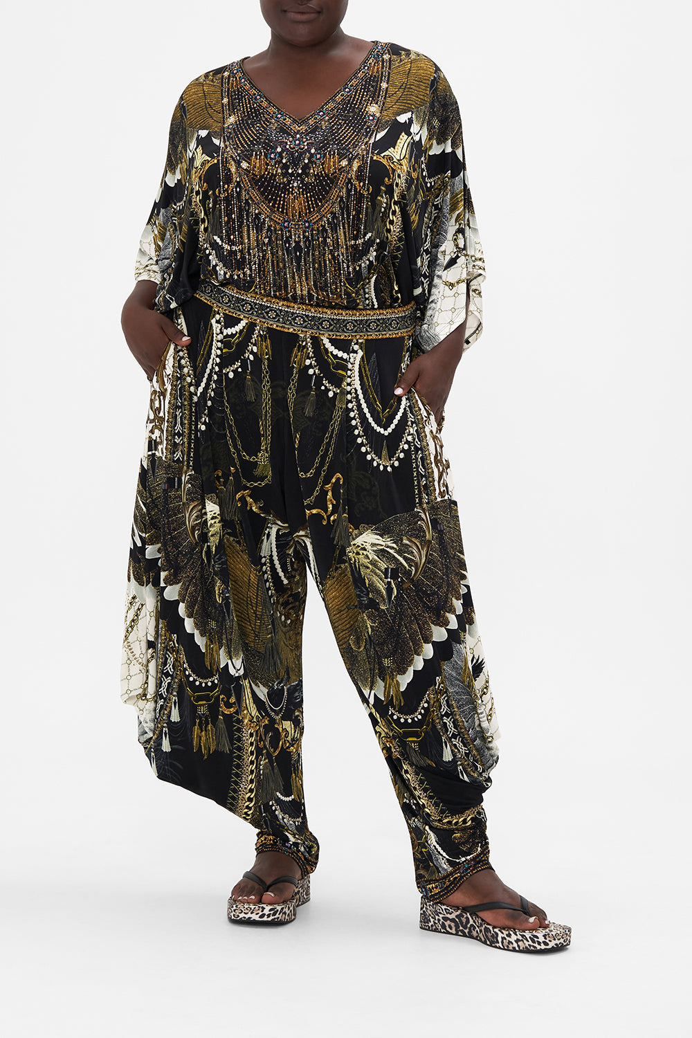 Front view of curvy model wearing CAMILLA plus size jersey drape pant in Ravin Raven print 